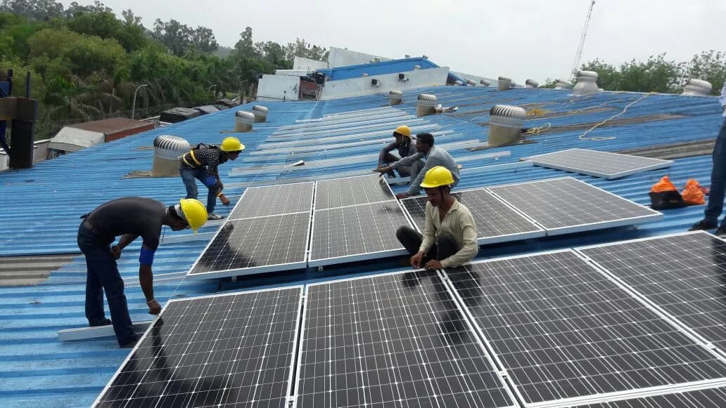 Installation team positioning rooftop solar modules at Pernod Ricard, Dera Bassi